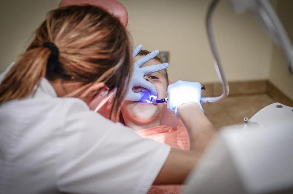 Dentist using a curing light to harden a tooth-colored filling
