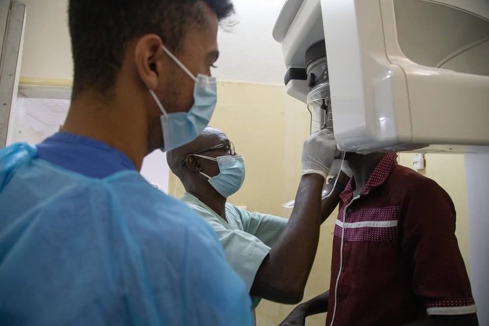 Dentist working on a patient while deciding between saving a tooth and pulling it