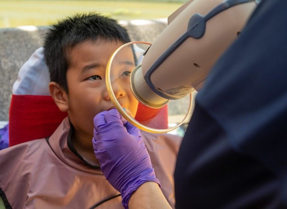 Patient positioned for a panoramic dental X-ray that shows developing wisdom teeth